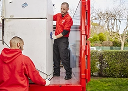 Junk King professionals loading a refrigerator onto a truck bed.