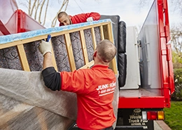 Junk King professionals loading a mattress onto a truck bed.