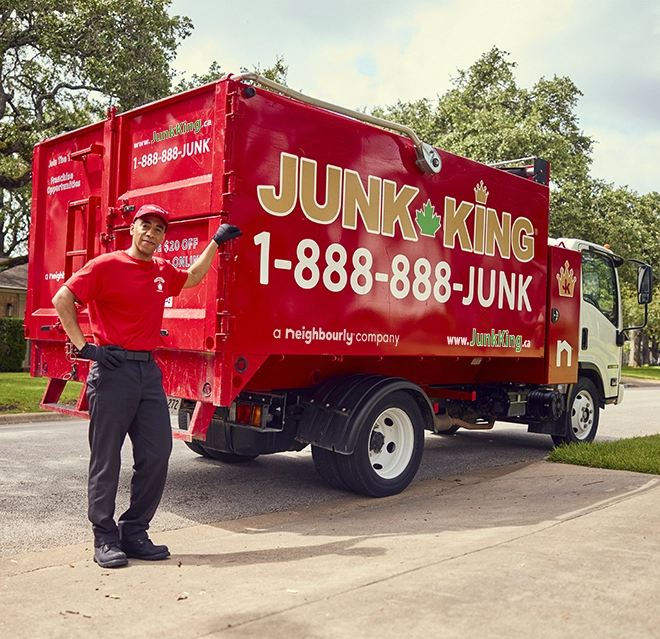 Junk King professional standing beside a red branded dump truck.