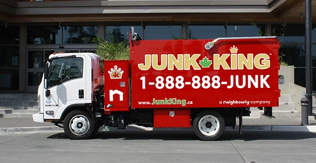A branded Junk King dump truck parked in front of a school.