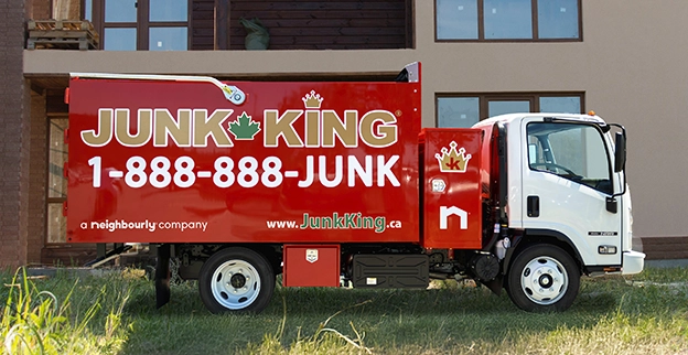 A branded Junk King dump truck parked outside of a building under construction.