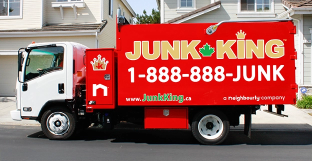 A branded Junk King dump truck parked on the street outside of a home.