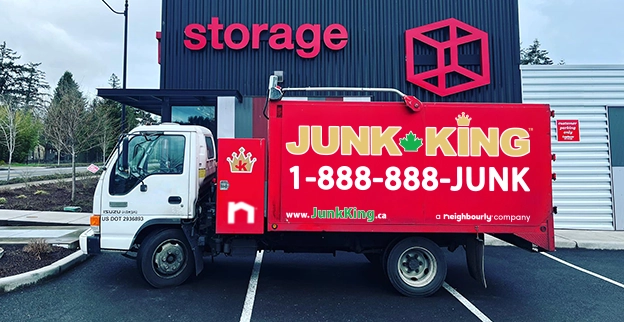 A branded Junk King dump truck parked outside of a storage facility.