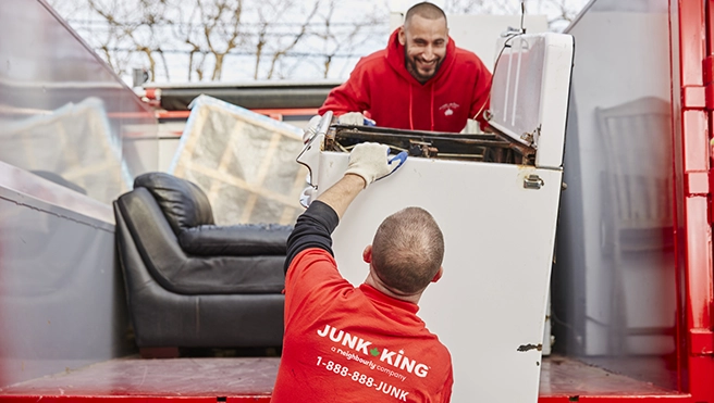 Junk King professionals loading a washing machine into the back of a truck.