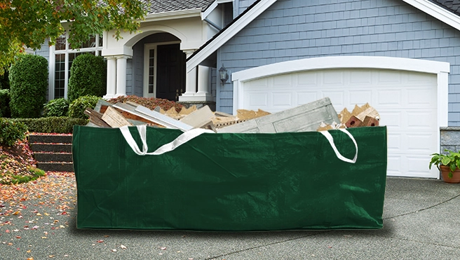 Green dumpster bag in a driveway outside of a home.
