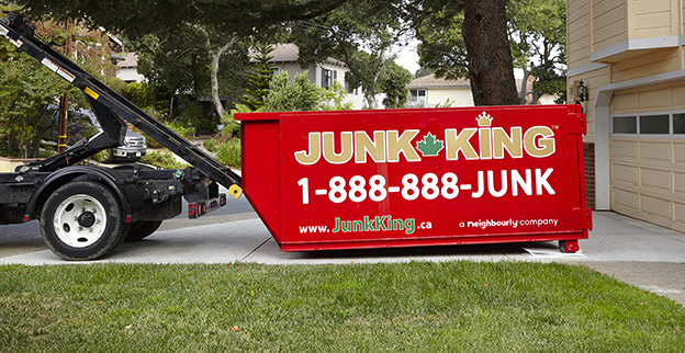 A red dumpster being delivered to a home.