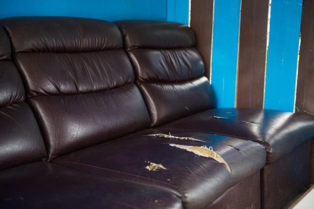 A leather couch with rips in it.