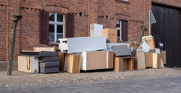 A pile of junk outside of a brick commercial building.