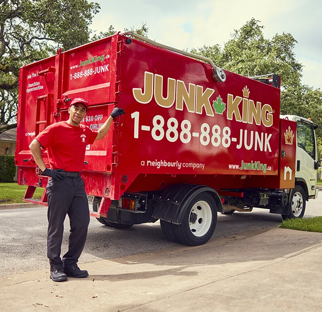 Junk King professional leaning his arm against a red Junk King dumpster truck.
