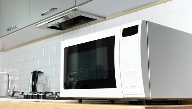 White microwave on a butcher block countertop.