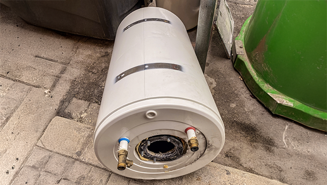 A disconnected water heater laying on its side.