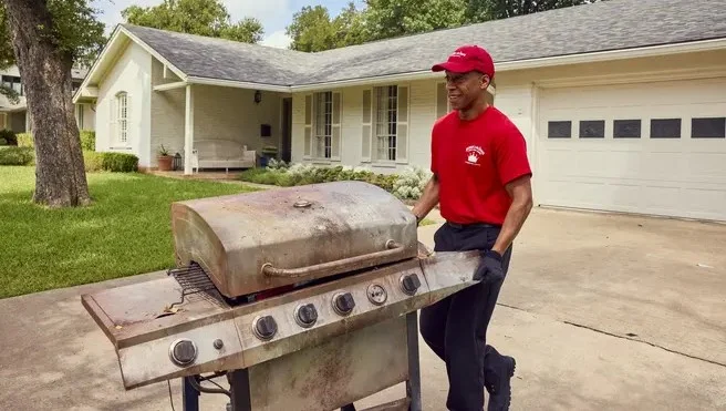 Junk King employee getting rid of an old grill.